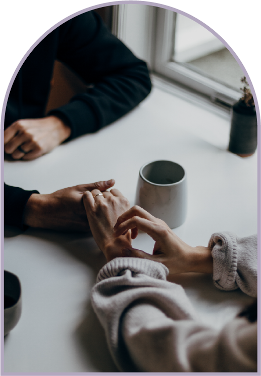 Domestic abuse survivors holding hands over coffee