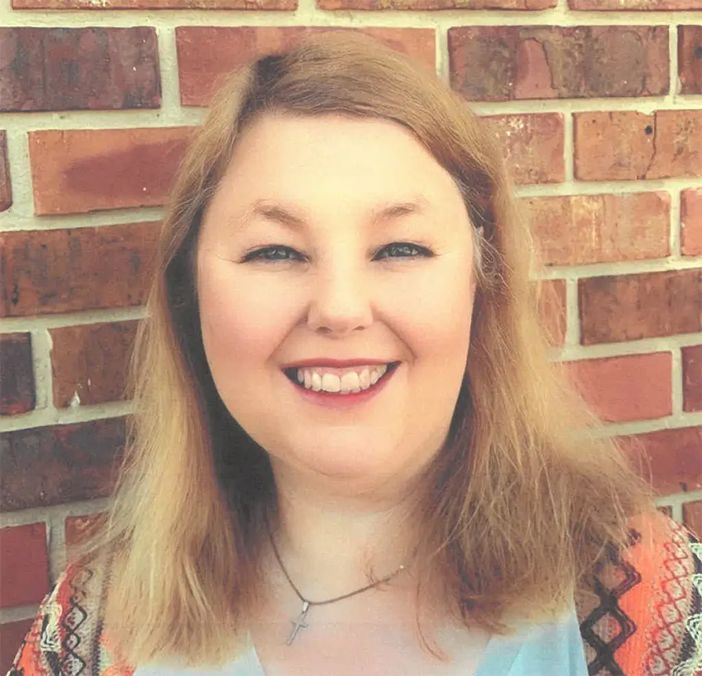 Stephany McTarsney smiling with a brick background